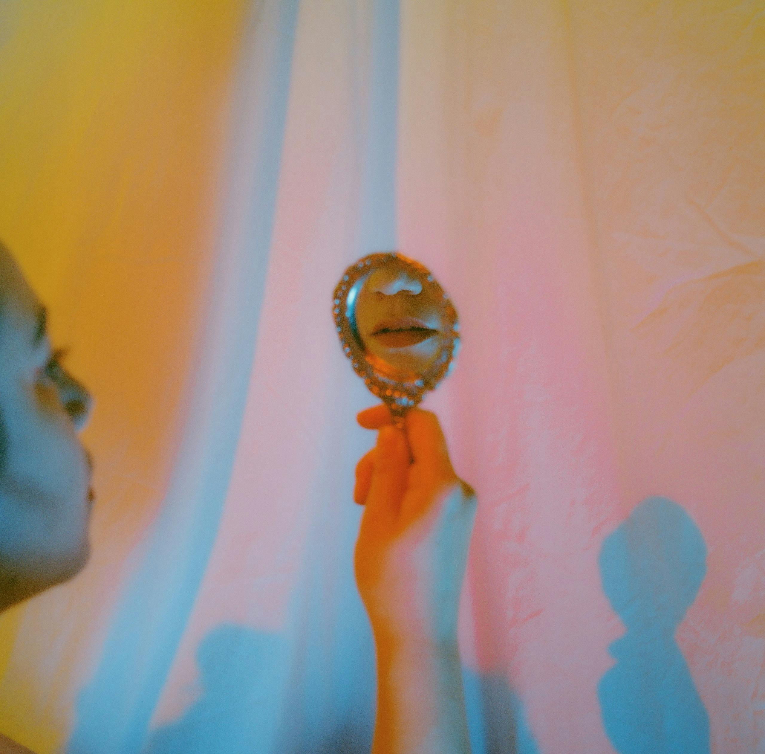 Woman looking at her reflection with studio lights captured on film by Natalie Carrasco